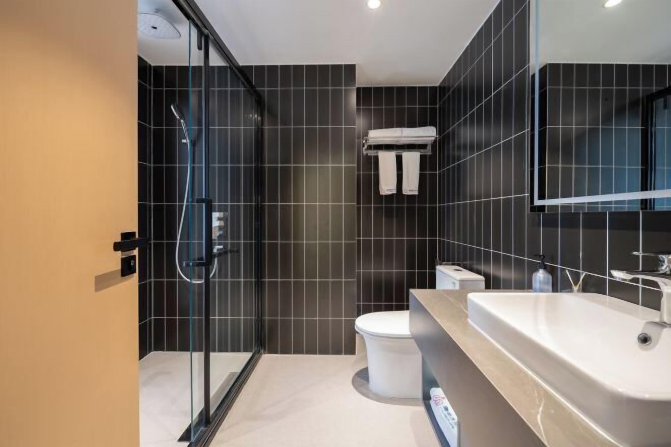 Une salle de bain moderne avec une douche à parois de verre, des toilettes blanches et un grand lavabo avec un miroir.
