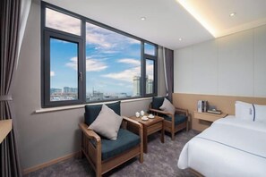 A hotel room with a large window, a bed, a small table, and a chair. - Mengzi Yufeng Hotel (Mengzi)