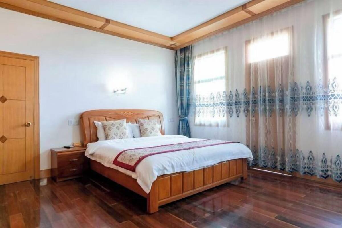 Un dormitorio con cama de madera, mesita de noche, armario y ventana con cortinas.
