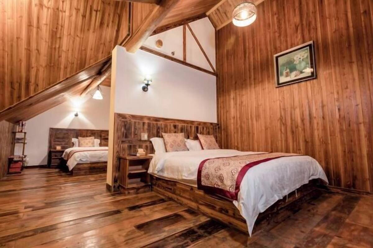 Un dormitorio rústico de madera con cama estilo loft, mesita de noche y lámpara fijada a la pared.
