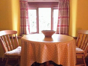 A dining table with a polka dot tablecloth, two wooden chairs, and a bowl on the table. - 2 bedroom accommodation in Hutton, near Weston-Super-Mare (Hutton, near Weston-Super-Mare)