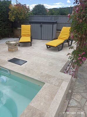 A poolside area with two yellow lounge chairs, a stone planter, and a grey fence in the background. - "La Casa di Gerlinde by Saint Martin" apartment with pool, pet friendly! (Saint-Martin-de-Valgalgues)