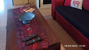 A living room with a wooden coffee table, red and black sofa, and a closed door with a decorative panel.