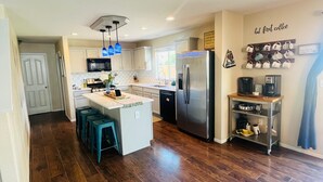 A modern kitchen with a central island, stainless steel appliances, and a coffee station.