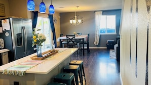 A modern kitchen with a central island, bar stools, and pendant lighting.