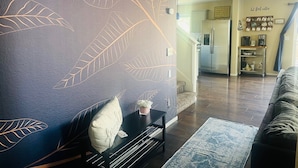 A living room with a dark blue wall featuring leaf patterns, a black coffee table, a sofa, and a rug.