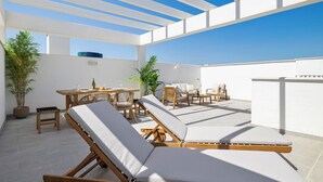 A rooftop terrace with lounge chairs, a dining table, and potted plants. - Casa Carmen - Rooftop Luxury Penthouse Estepona (Estepona)