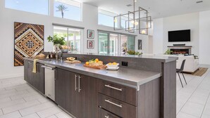 A modern kitchen with a large island, built-in appliances, and a flat-screen TV. - The Polo Villas by AvantStay (La Quinta)