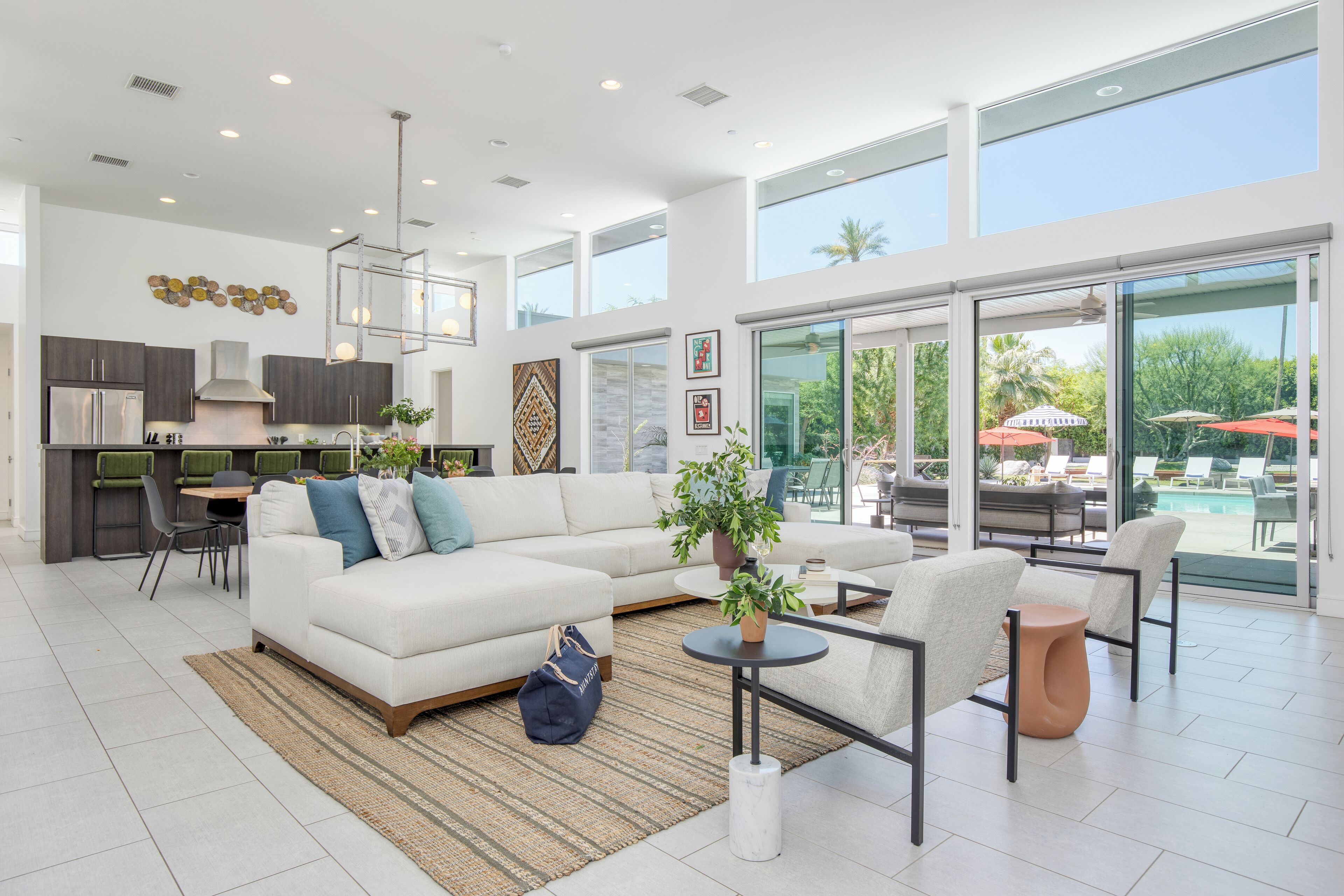 A spacious living area with a white sofa, a dining table, and a kitchen in the background.