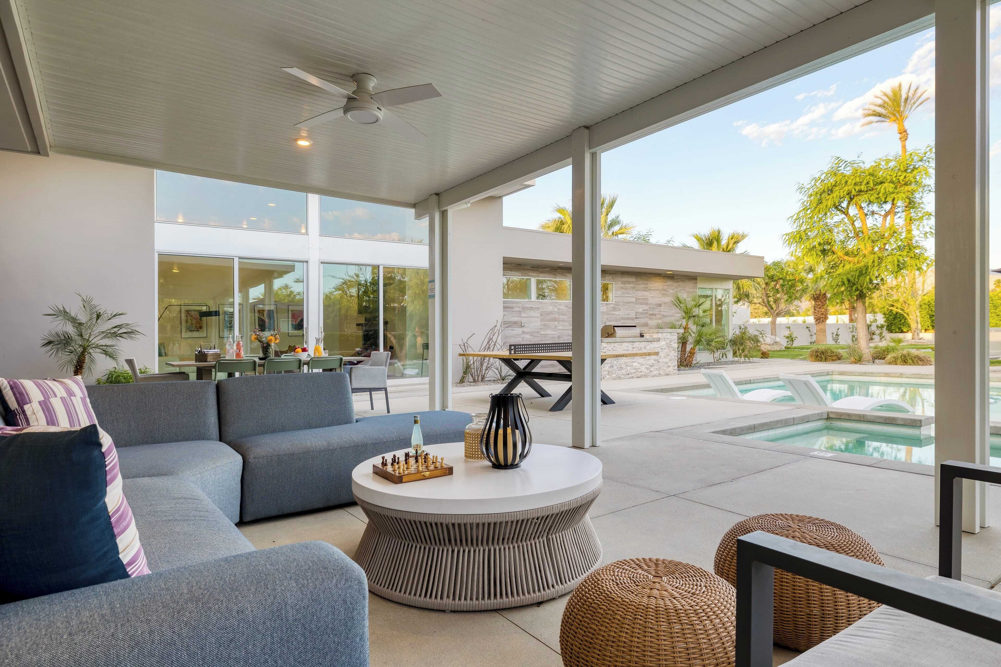 Un espace de vie extérieur moderne comprenant une piscine, une table basse ronde et un canapé.