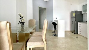 Una cocina moderna con refrigerador, microondas y un comedor con mesa y sillas de vidrio.