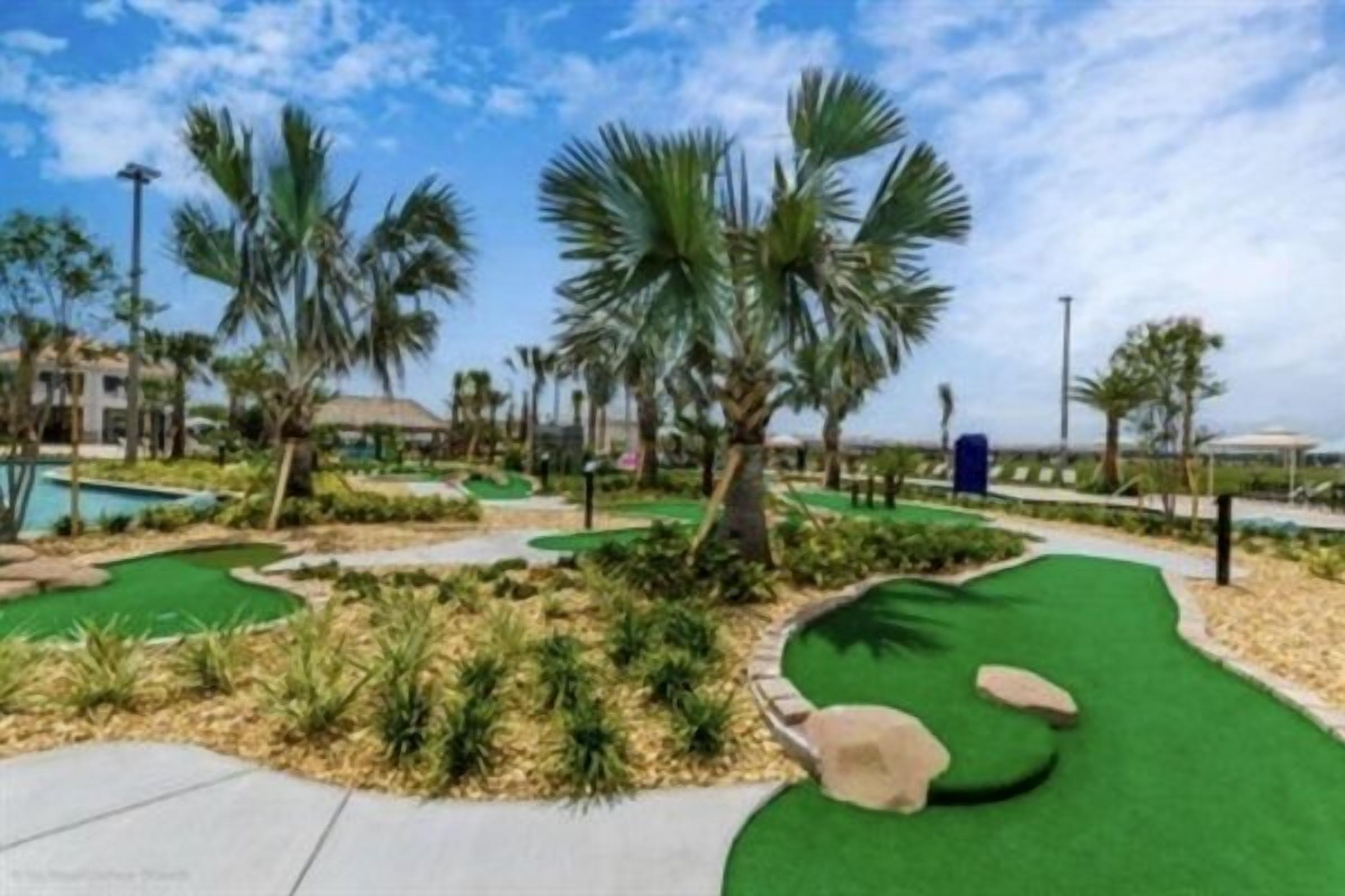 A landscaped area with palm trees, a pool, and a golf course.