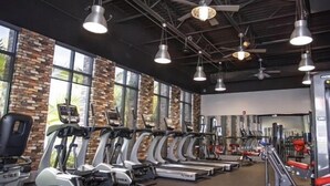 Une salle de sport équipée de plusieurs tapis de course, de vélos d’exercice et d’appareils de musculation.