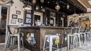 Eine Bar mit einer Theke, Barhocker und hängenden Lampen.