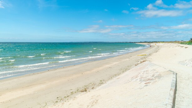 Ein Strand mit klarem, blauem Wasser und einem sandigen Ufer.