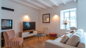 Ein modernes Wohnzimmer mit Sofa, Fernseher, Couchtisch und Sessel.