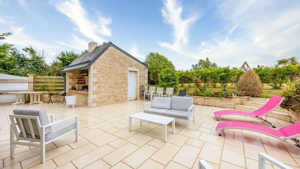 A patio with outdoor furniture, a stone building, and a garden. - La Renardière - Maison avec vue mer (Barneville-Carteret)