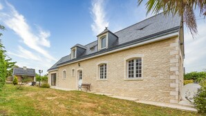 A stone house with a sloped roof, a small porch, and a grassy yard. - La Renardière - Maison avec vue mer (Barneville-Carteret)