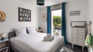 Une chambre à coucher bien rangée, avec un lit, une table de chevet, une lampe, des tableaux encadrés et une commode.
