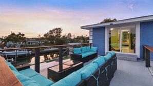 A modern outdoor deck with wicker furniture and a view of the marina.