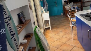A kitchen with a tiled floor, a blue door, and a television.