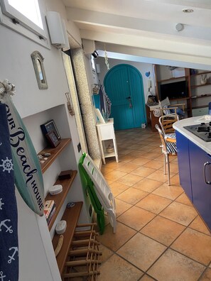 A kitchen with a tiled floor, a blue door, and a television.