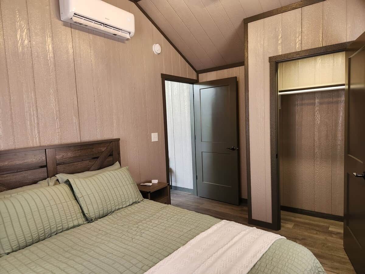 A bedroom with a bed, a wardrobe, and a door leading to another room.