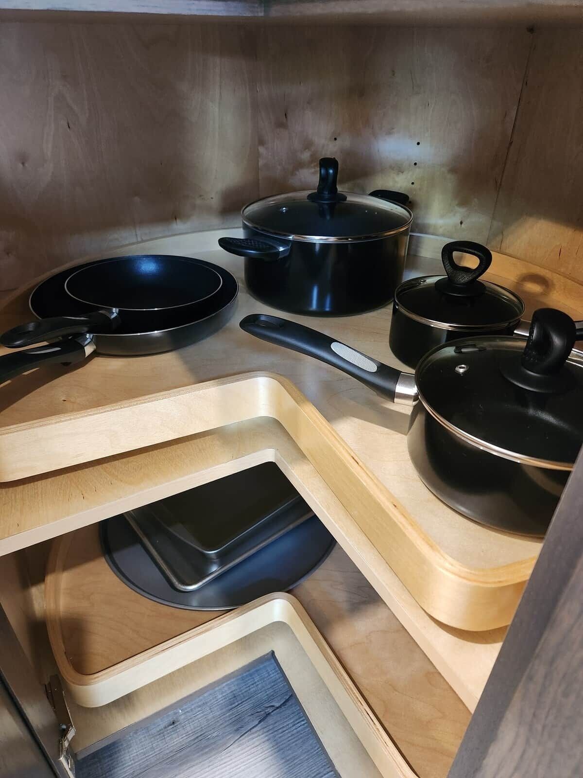 Una cocina con estufa, sartén, olla y bandeja sobre encimeras de madera.