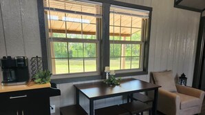 A kitchen with a table, two chairs, a coffee maker, and a window with blinds.