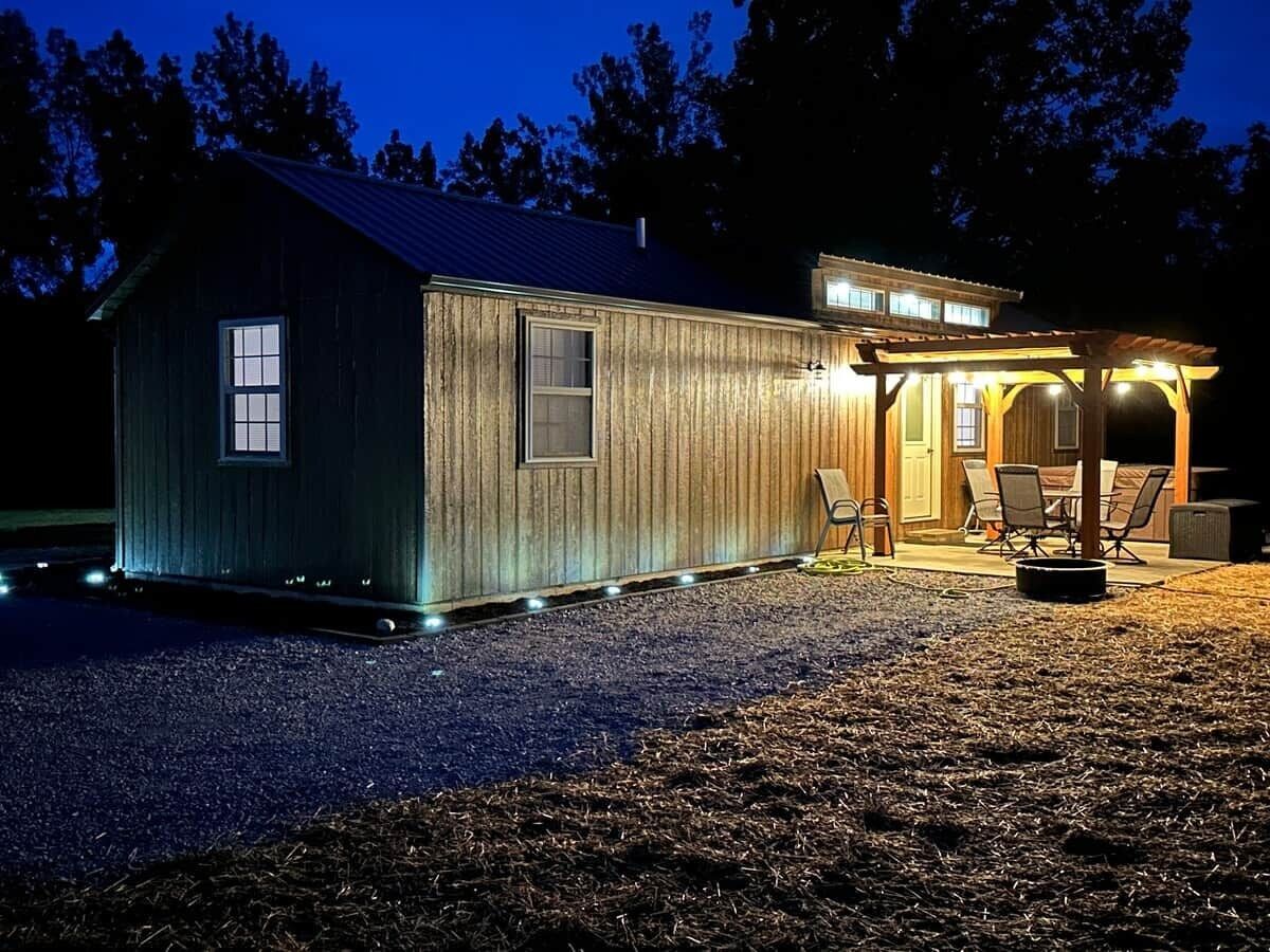 A wooden cabin with a covered patio and outdoor seating.