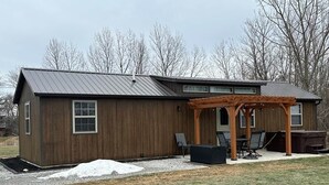 A single-story building with a covered patio area, a hot tub, and a fire pit.