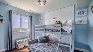 A bunk bed room with a view of the outdoors, a window with curtains, and wall-mounted artwork. - Views of Osage Golf Course & Osage River, 3 Balconies, Game Room, Sleeps 9 (Kaiser)