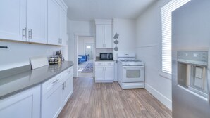 Una cocina moderna con armarios blancos, un refrigerador de acero inoxidable, un microondas y una estufa.