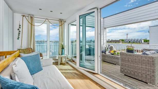 A balcony with a sofa, wicker furniture, and a view of a cityscape.