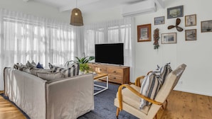 A modern living room with a sofa, armchair, TV, and artwork on the wall. - High Noon - Pet Friendly Eden (Eden)