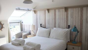 Ein Schlafzimmer mit Bett, Nachttisch, Lampe und Blick ins Freie.