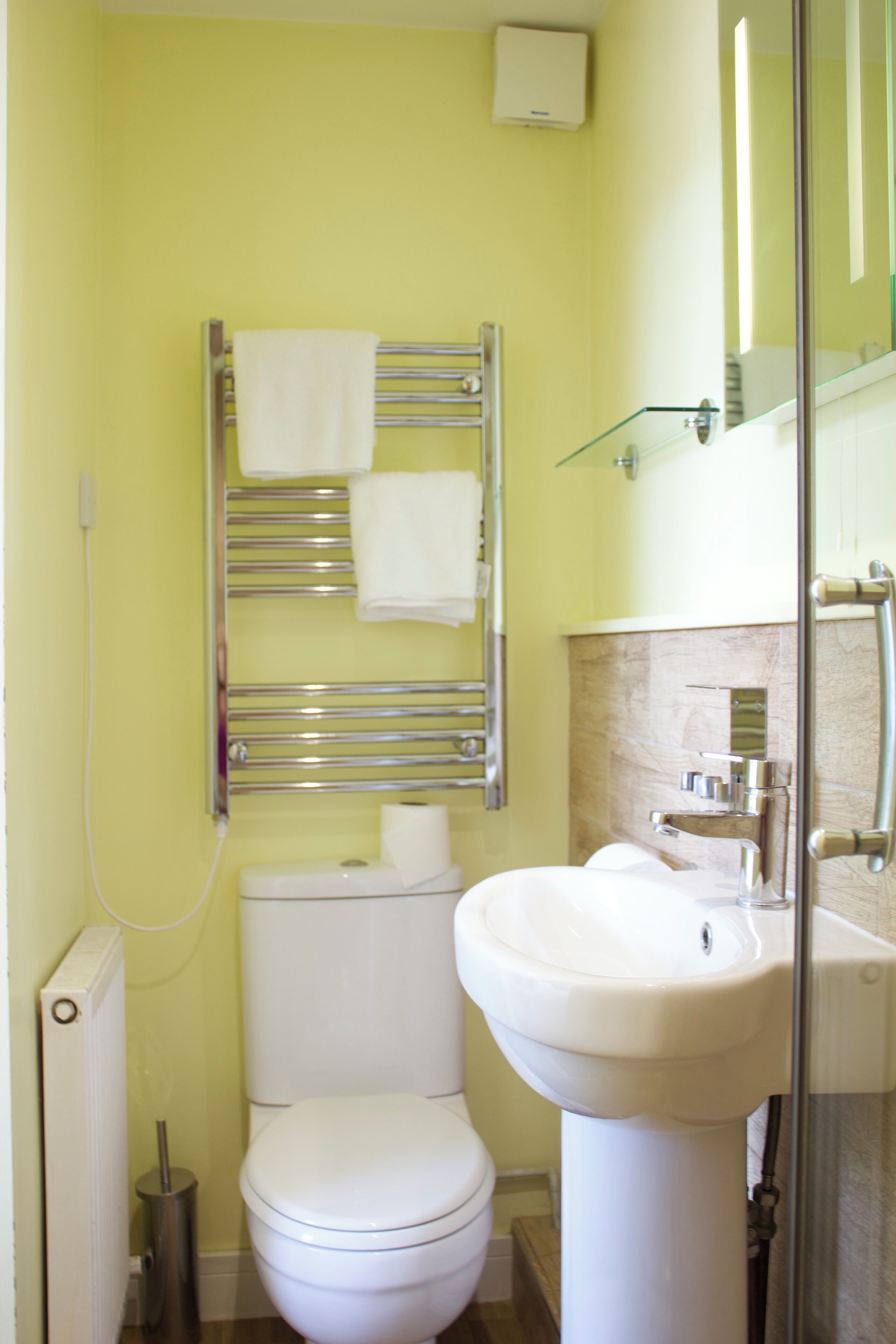 A bathroom with a toilet, sink, towel rack, and glass shower enclosure.