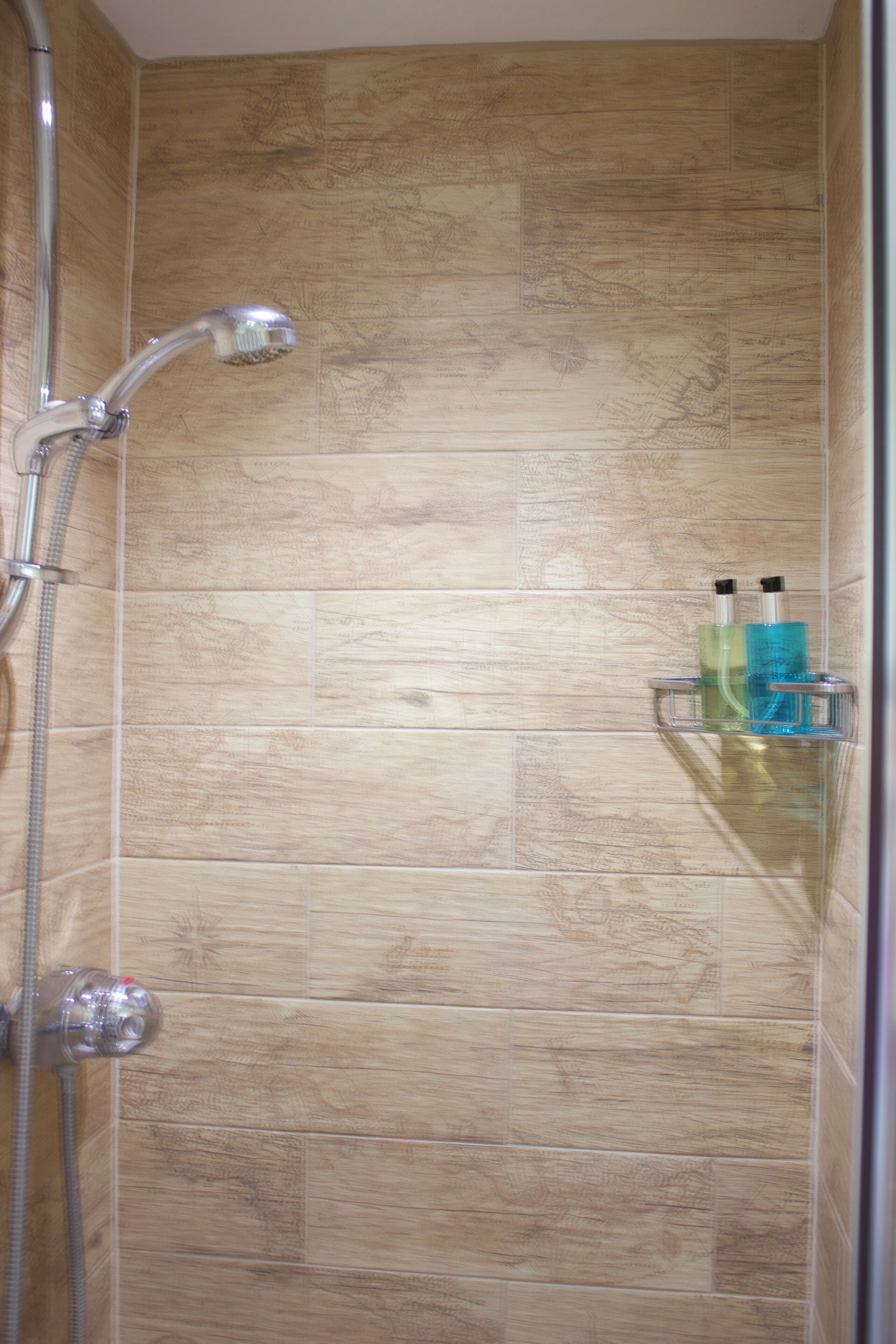 Een douche met houten tegels en een glazen plank voor toiletartikelen.