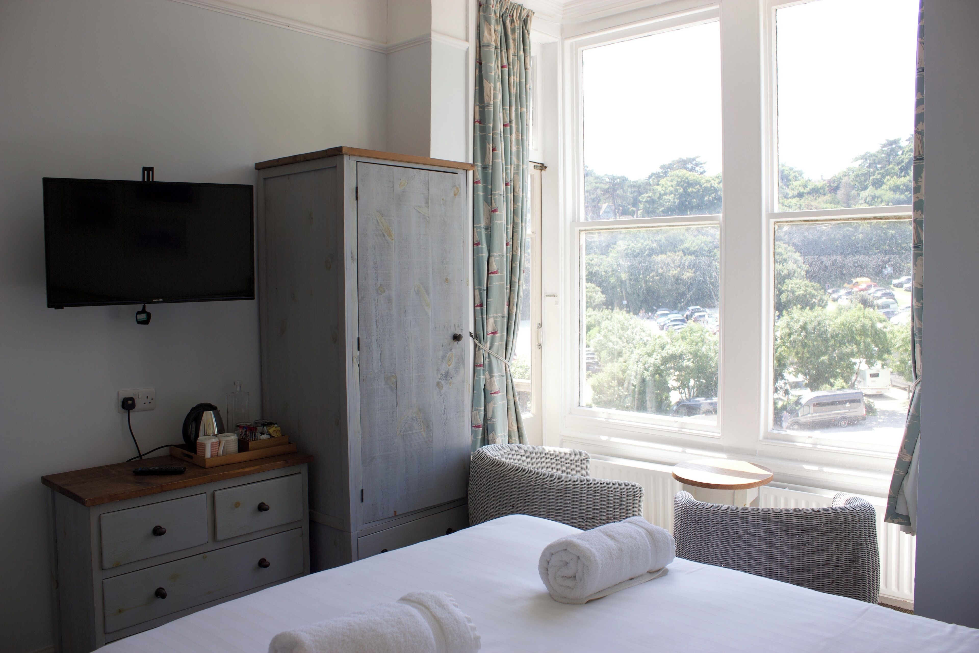 Una camera d'albergo con un letto, una televisione a parete, un armadio, una finestra con vista sull'esterno e un tavolino.