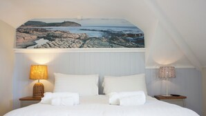 A bedroom with a bed, two bedside tables, a lamp on each table, and a large picture above the bed. - Durdle Door Hotel (Wareham)