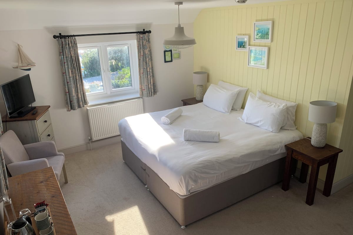 A neatly arranged bedroom with a bed, bedside tables, a desk, and a television.