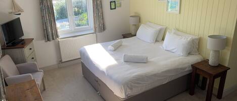 A neatly arranged bedroom with a bed, bedside tables, a desk, and a television.
