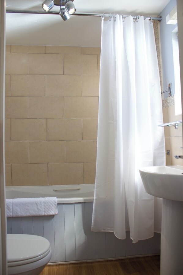 A bathroom with a bathtub, toilet, and sink. - Durdle Door Hotel (Wareham)