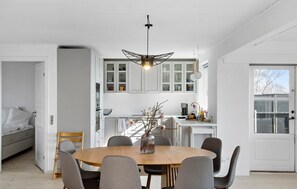 A modern kitchen with white cabinets, a wooden dining table, and grey chairs. - 4 bedroom gorgeous home in Rude (Rude)