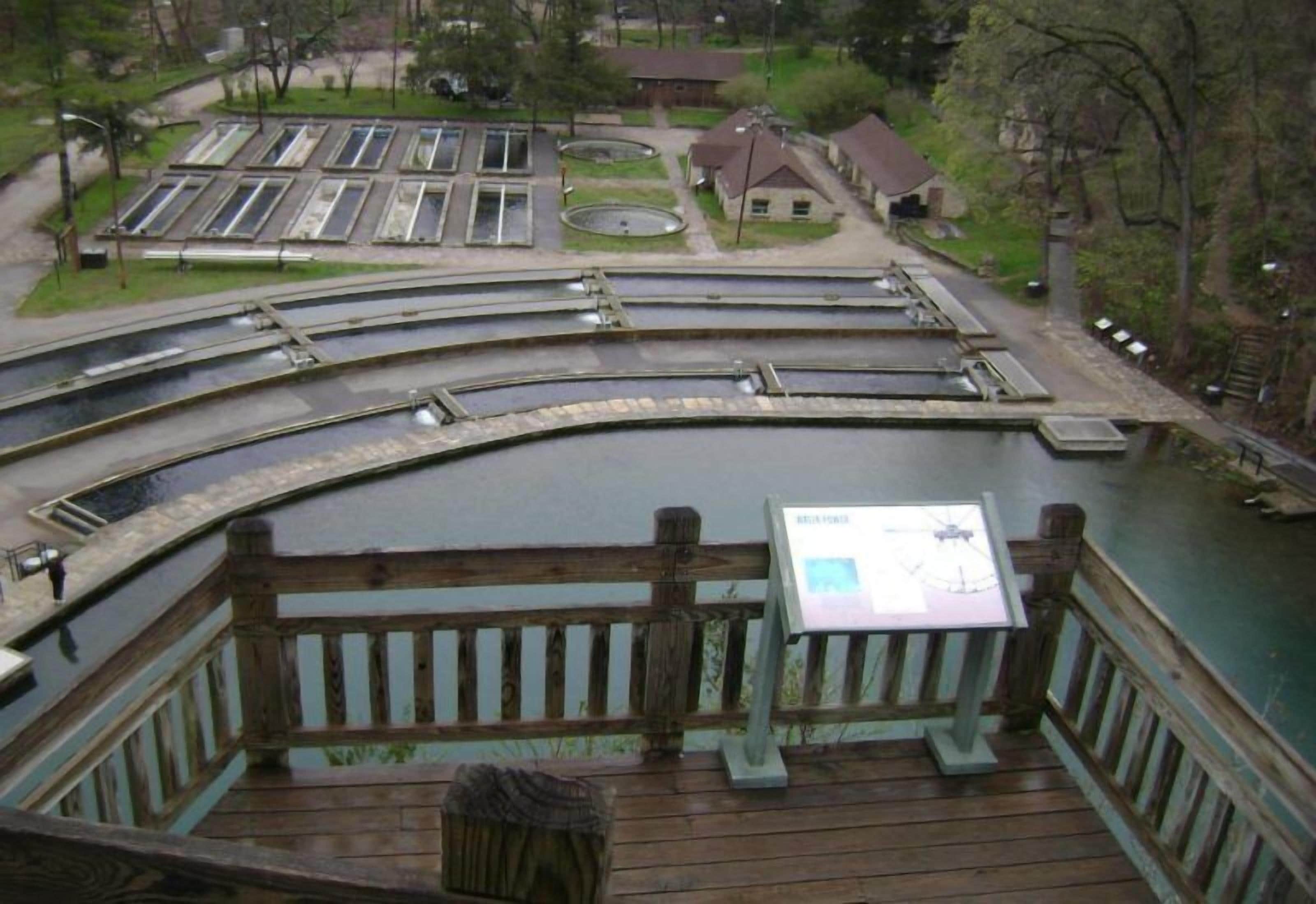 Una terraza de madera con un letrero, con vista a una serie de canales acuáticos y un pequeño edificio al fondo.