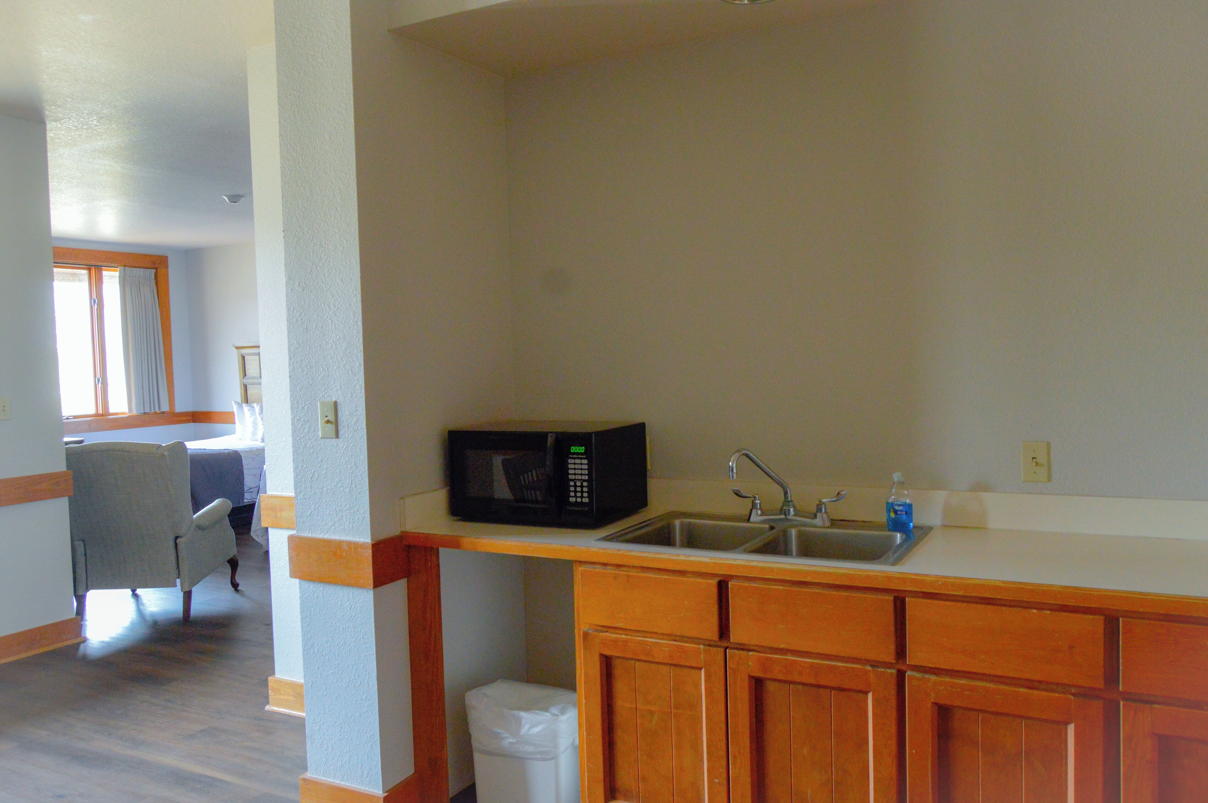 A kitchen with wooden cabinets, a microwave, and a sink.