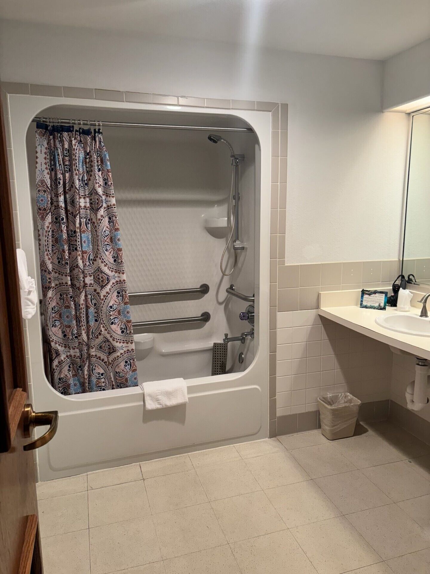 Une salle de bain équipée d’une baignoire à porte, d’une douche, d’un lavabo et d’un miroir.