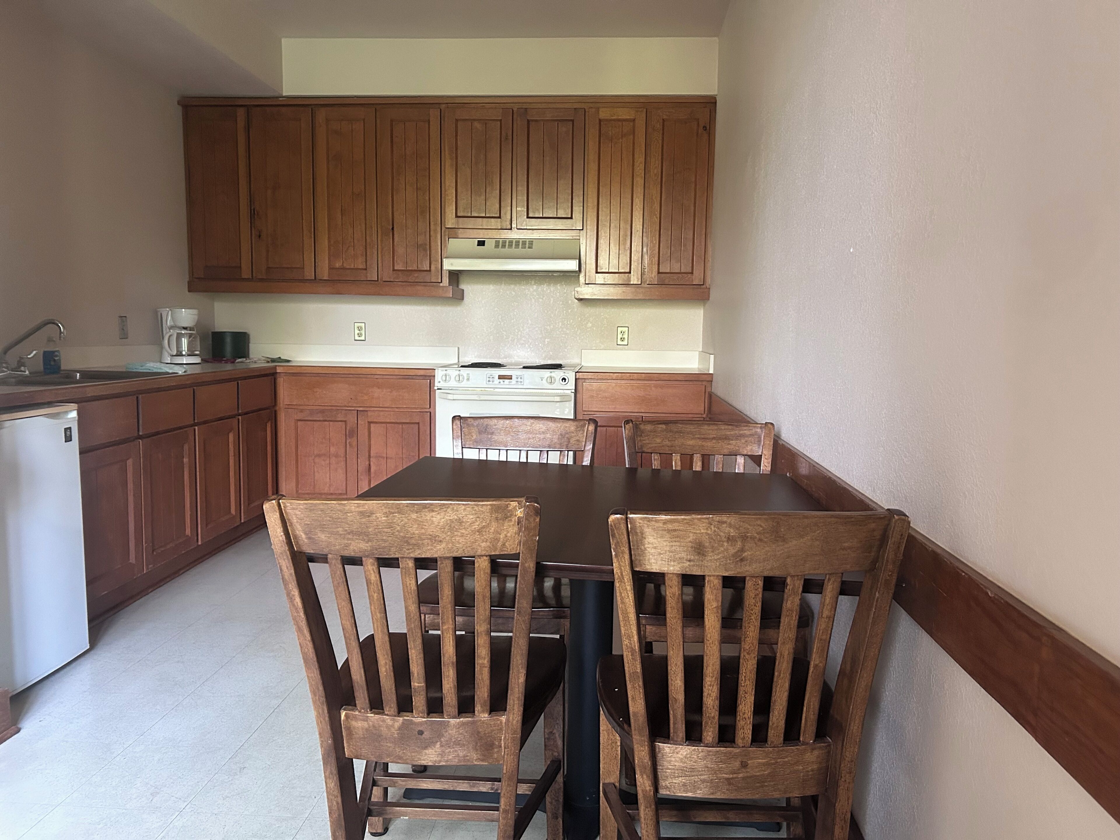 A kitchen with wooden cabinets, a stove, and a dining table with chairs.