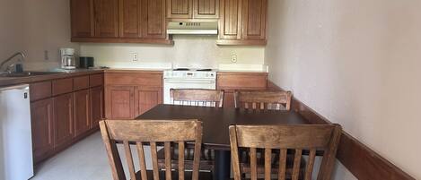 A kitchen with wooden cabinets, a stove, and a dining table with chairs.
