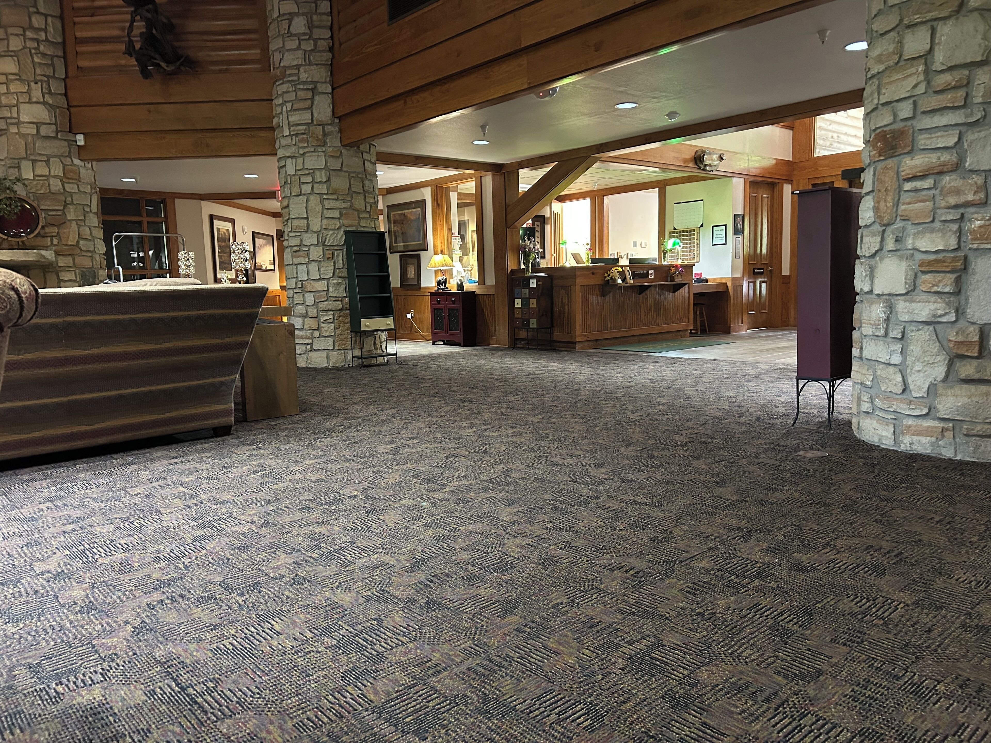 Un hall d’entrée spacieux avec un comptoir d’accueil, des piliers en pierre et une moquette à motifs.
